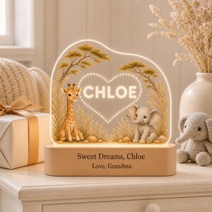 May include: A custom acrylic night light featuring a giraffe and elephant illustration with a central heart shape containing the name CHLOE. The light sits on a wooden base engraved with the text Sweet Dreams, Chloe Love, Grandma.