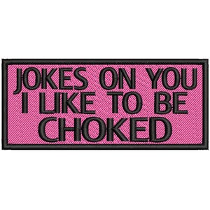 May include: Embroidered patch with the text "JOKES ON YOU I LIKE TO BE CHOKED" in black on a pink background. The patch has a black border and a textured appearance.