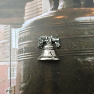 Puede incluir: Una r&eacute;plica de plata de la Campana de la Libertad, un famoso monumento de Filadelfia, Pensilvania. La campana est&aacute; inscrita con "Proclaim Liberty Throughout All The Land" y "In Philadelphia Pass And Stow" en el lateral.