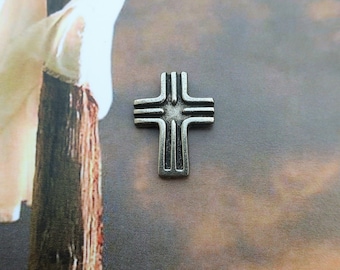 Puede incluir: Una cruz de plata con un diseño sencillo, que presenta un círculo central y cuatro líneas que se extienden hacia afuera. La cruz se coloca sobre un fondo de cielo nublado.