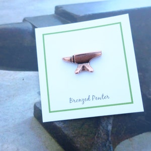 May include: A small, bronze-colored pewter anvil pin on a white card with green trim. The card reads "Bronzed Pewter".