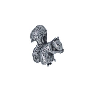 May include: A silver-colored squirrel figurine with a bushy tail, sitting on its haunches and holding a nut in its paws.