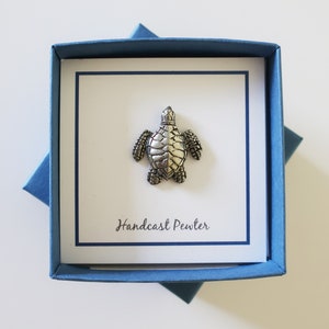 May include: A silver pewter turtle figurine in a blue box with the text "Handcast Pewter".