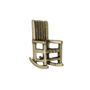 Pode incluir: Uma figura de cadeira de balan&ccedil;o de metal dourado. A cadeira tem um encosto de ripas e um assento de design simples.