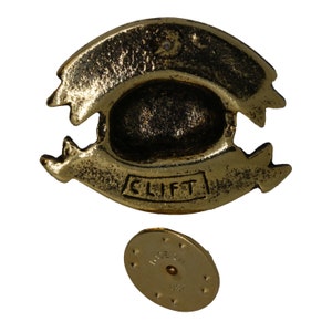 May include: Gold-toned metal door knocker with a banner design and the word "CLIFT" inscribed. The knocker is attached to a round, gold-toned metal base with the words "MADE IN USA" inscribed.