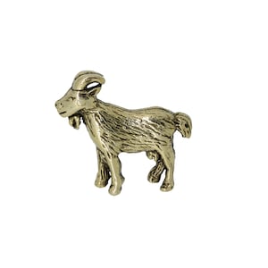 May include: A gold-coloured metal figurine of a goat standing on all four legs. The goat has a detailed face and fur texture.