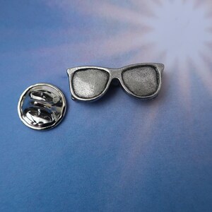 Puede incluir: Pin de gafas de sol plateadas con cierre de seguridad. El pin es un art&iacute;culo de novedad y no est&aacute; dise&ntilde;ado para usarse como un par real de gafas de sol.