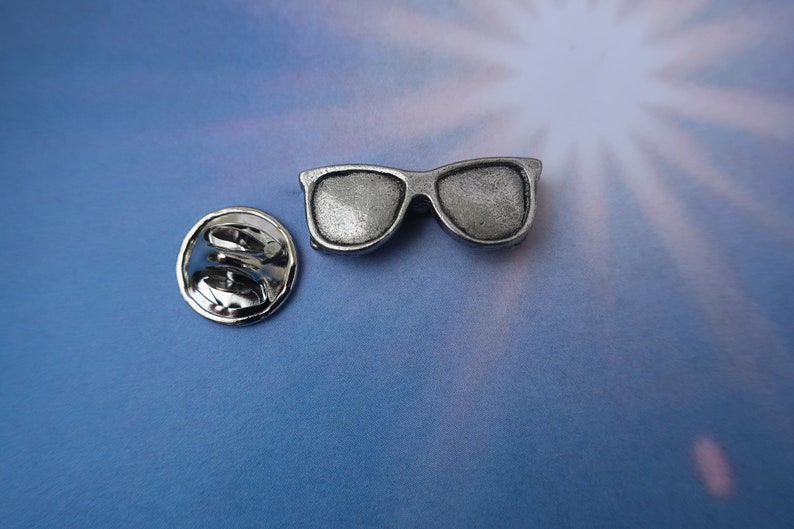 Puede incluir: Pin de gafas de sol plateadas con cierre de seguridad. El pin es un art&iacute;culo de novedad y no est&aacute; dise&ntilde;ado para usarse como un par real de gafas de sol.
