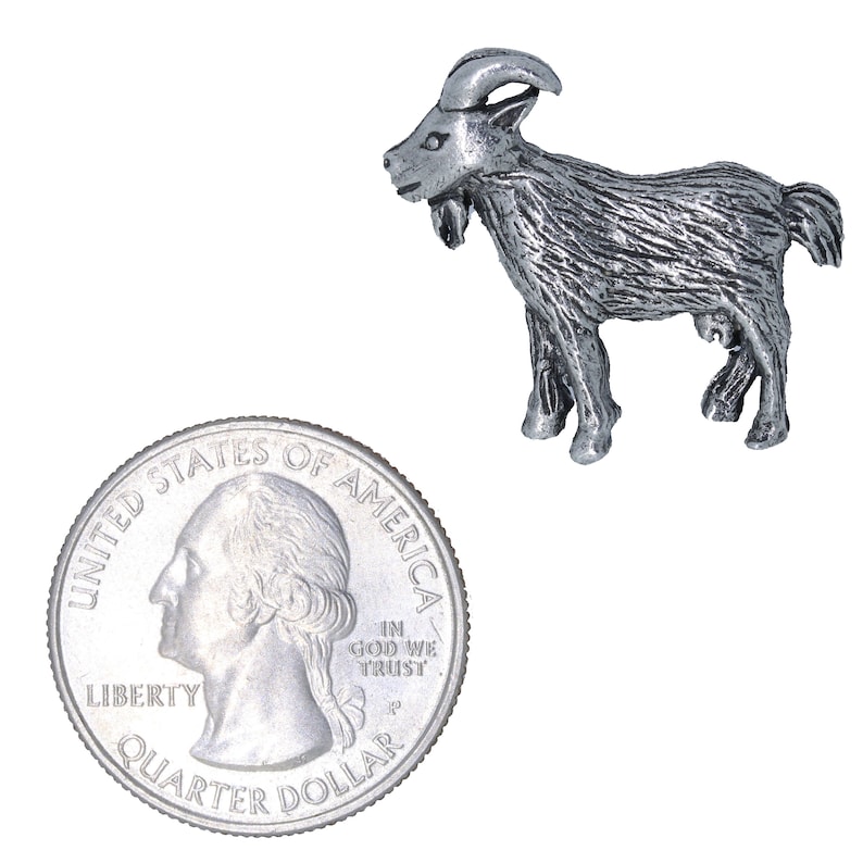 May include: A silver-colored pewter goat figurine, standing on a white background. The goat is about the size of a US quarter.