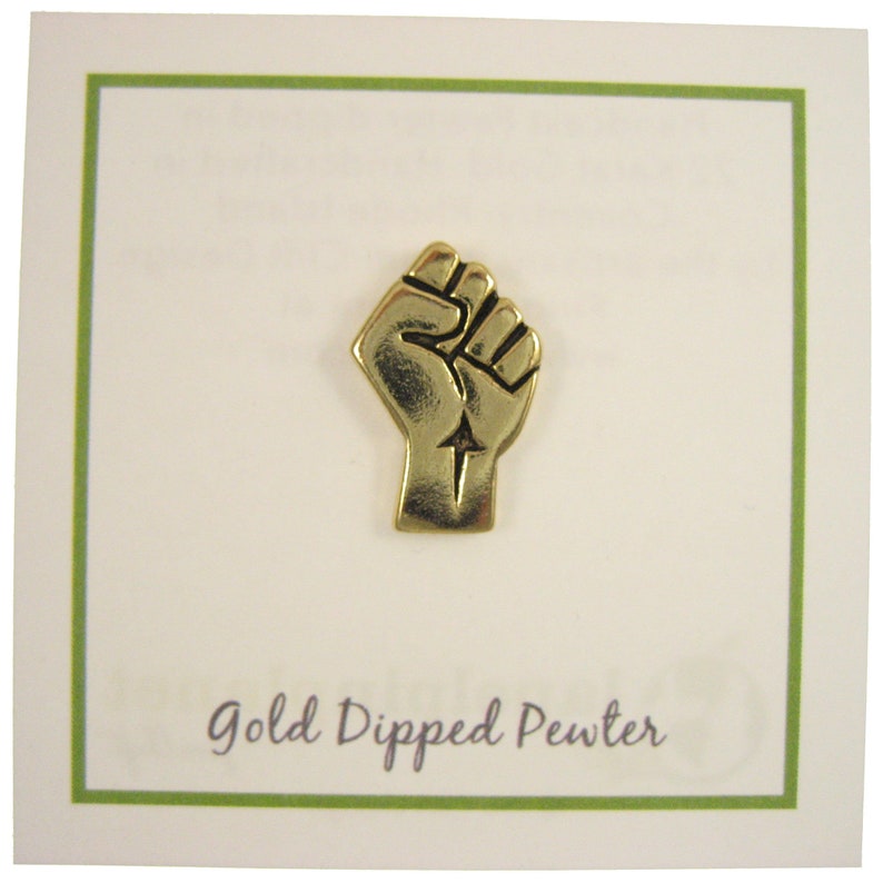 May include: Gold-dipped pewter pin featuring a raised fist with an arrow pointing upwards. The pin is on a white card with the text "Gold Dipped Pewter".
