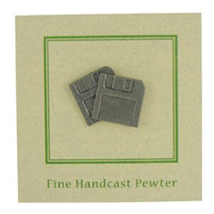 May include: Two small, gray pewter floppy disk pins on a beige card with a green border. The text "Fine Handcast Pewter" is printed in a dark green font below the pins. The pins are a retro design.