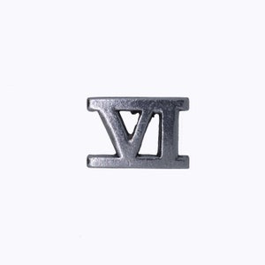 May include: A silver metal charm in the shape of the Roman numeral VI.