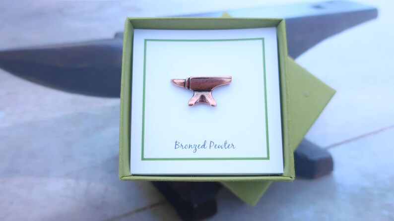 May include: A small, bronze-colored pewter anvil pin in a green gift box with a white card that says "Bronzed Pewter".