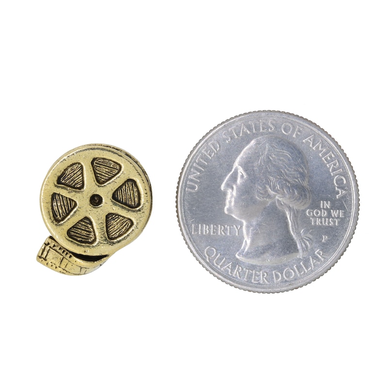 May include: A gold-colored metal film reel charm, about the size of a US quarter, with a detailed design. The charm is a popular choice for jewelry making and crafting.