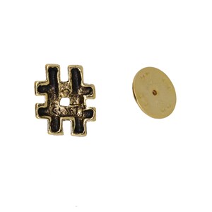 May include: Gold-colored metal pin with a black enamel hashtag symbol. The back of the pin has a circular metal backing.