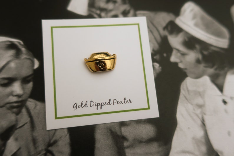 May include: Gold-dipped pewter nurse's hat pin. The pin is on a white card with green trim and the text "Gold Dipped Pewter".