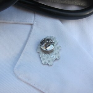 May include: Silver pin with a heart design and the word "CLIFT" on it.