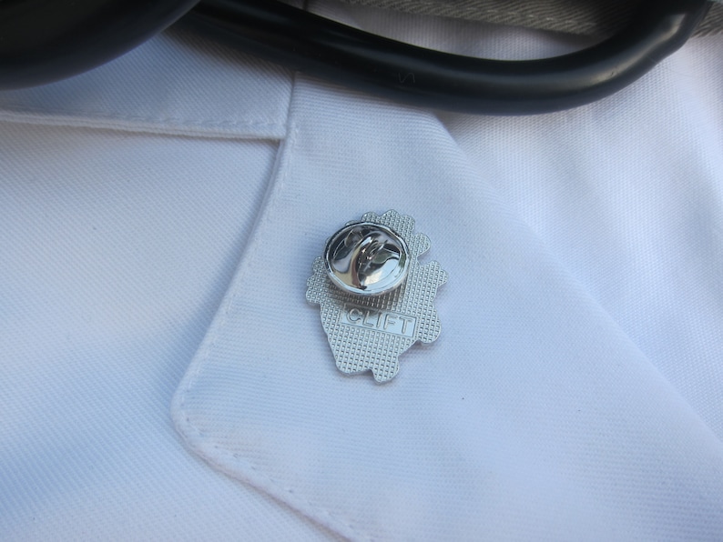 May include: Silver pin with a heart design and the word "CLIFT" on it.