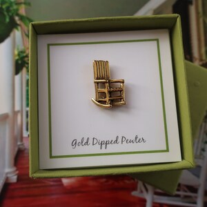 Pode incluir: Um pequeno amuleto de cadeira de balan&ccedil;o de estanho banhado a ouro em uma caixa de presente verde com um cart&atilde;o branco que diz "Gold Dipped Pewter".