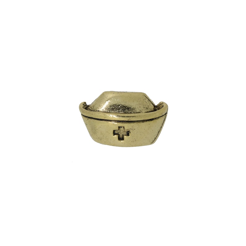 May include: Gold-toned metal nurse's cap charm with a red cross in the center.