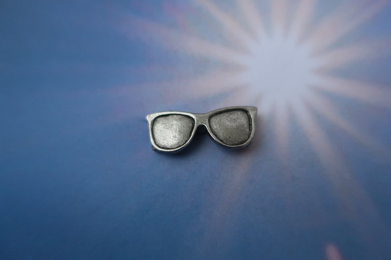 Puede incluir: Encanto de plata en forma de gafas de sol. El encanto es peque&ntilde;o y detallado.