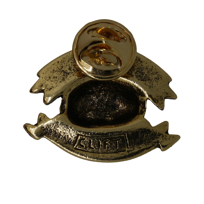 May include: Gold-toned metal pin with a banner that reads "SLIFT". The pin has a detailed design and a safety clasp on the back.