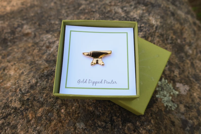 May include: A gold-dipped pewter anvil pin in a green box with a white card that says "Gold Dipped Pewter".