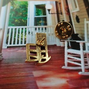 Pode incluir: Pin de metal dourado com um design de cadeira de balan&ccedil;o com a palavra "CLIFT" no verso. O pin &eacute; feito nos Estados Unidos.