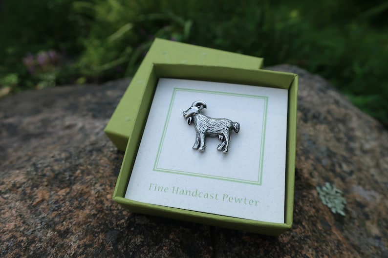 May include: A silver pewter goat figurine in a green gift box with the text "Fine Handcast Pewter".
