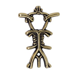 May include: A bronze-colored pendant with an intricate, symmetrical design. The pendant features a central vertical element with horizontal and curved extensions, and a decorative openwork base. The overall shape is reminiscent of a stylized figure or symbol.
