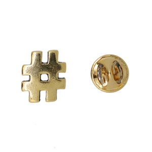 May include: Gold-colored metal pin with a hashtag symbol. The back of the pin has a safety clasp.