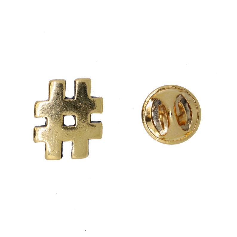 May include: Gold-colored metal pin with a hashtag symbol. The back of the pin has a safety clasp.