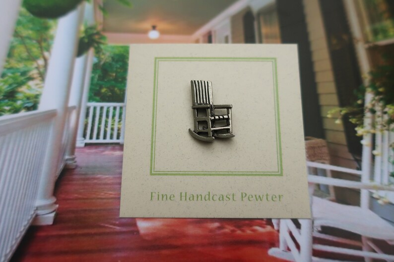 Pode incluir: Um amuleto de cadeira de balan&ccedil;o de peltre prateado com o texto "Fine Handcast Pewter" em um cart&atilde;o.