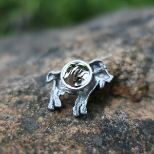 May include: Silver-toned metal pin featuring a detailed depiction of a goat. The pin has a safety clasp on the back.