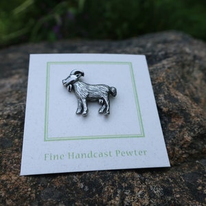 May include: A silver pewter goat figurine on a white card with the text "Fine Handcast Pewter".