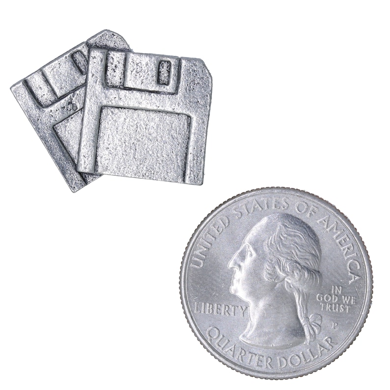 May include: Two silver-colored floppy disk-shaped objects are displayed next to a quarter. The quarter shows a profile of George Washington and the words "Quarter Dollar". The floppy disks are detailed with rectangular cutouts.