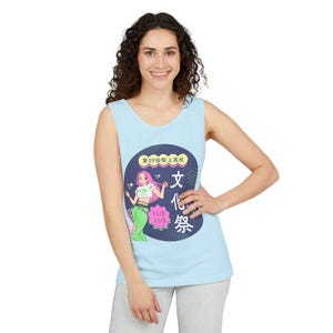 May include: Light blue tank top featuring a graphic of a mermaid with pink hair and the text "文化祭" in Japanese. The graphic is inside a navy blue circle. The tank top is sleeveless and made of a soft material.