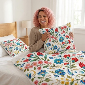 Puede incluir: Un juego de cama blanco con funda de almohada a juego que presenta un vibrante patrón floral con tulipanes rojos, flores azules y pequeñas flores amarillas sobre tallos verdes. La tela muestra un diseño botánico repetitivo.