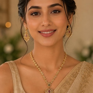 May include: A gold necklace featuring a central pendant with a teardrop-shaped red stone, small green accents, and dangling white beads. Matching gold drop earrings with red stones and white bead accents complement the necklace design.