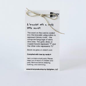 This is showing the back of the bracelet card with text that says a bracelet with a nerdy little secret. The silver represents the one and the clear represents the zero.