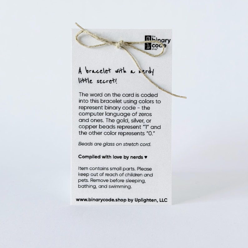 This is showing the back of the bracelet card with text that says a bracelet with a nerdy little secret. The silver represents the one and the clear represents the zero.