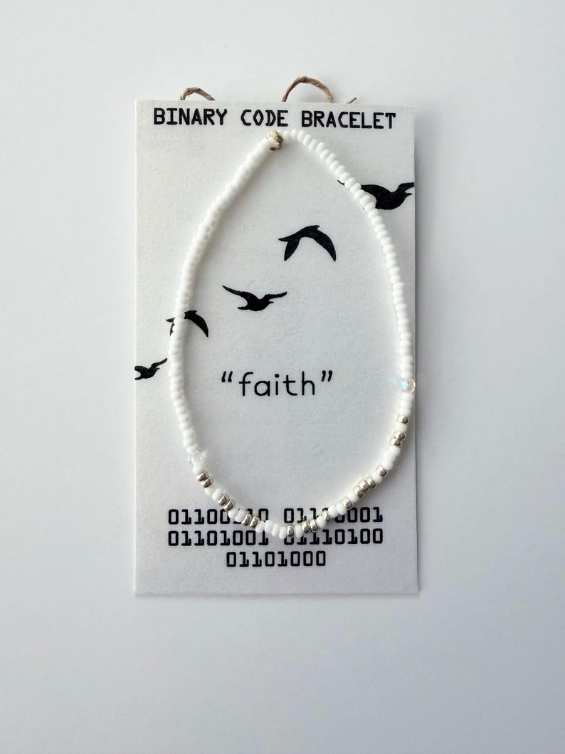 May include: A beaded bracelet made of small white and metallic silver beads on a white display card. The card features the text "BINARY CODE BRACELET" and "faith" with black bird silhouettes and binary code printed at the bottom.