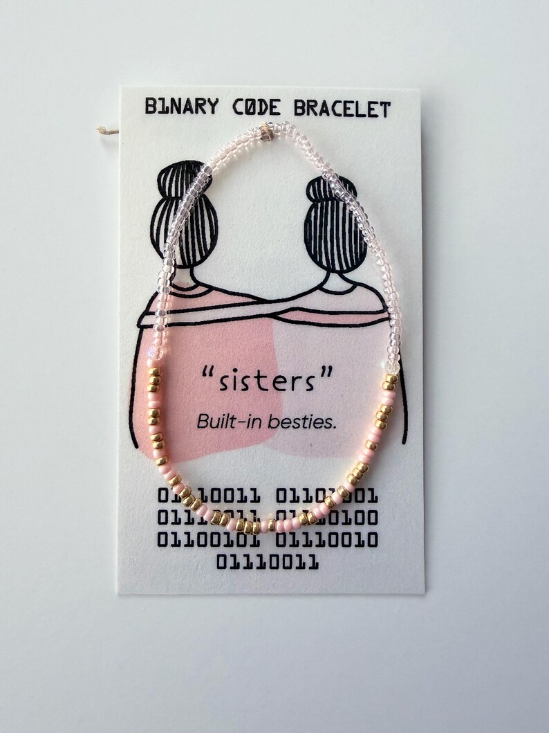 May include: A beaded bracelet featuring clear, light pink, and metallic gold seed beads arranged on a white display card. The card displays the text "BINARY CODE BRACELET", "sisters", "Built-in besties.", and a series of binary code numbers.