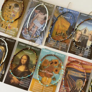 Puede incluir: Una colección de pulseras de código binario exhibidas en tarjetas con obras de arte famosas. Las pulseras tienen cuentas de colores y están etiquetadas con palabras como "joy", "dreamer" y "smile". Las tarjetas tienen código binario en la parte inferior.