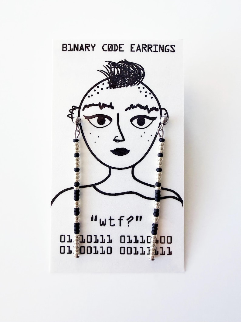 May include: Binary code earrings with black and silver beads hanging from a card with a drawn face and the text "BINARY CODE EARRINGS". The card also has the text "wtf?" and binary code.