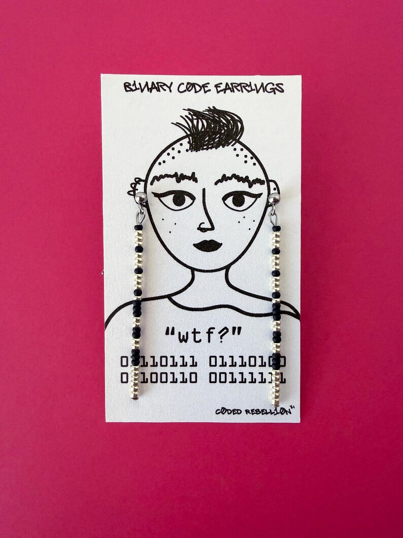 K&ouml;nnte beinhalten: Ohrringe mit schwarzem und goldenem Perlenbesatz, pr&auml;sentiert auf einer wei&szlig;en Karte mit handgezeichnetem Gesicht. Die Karte tr&auml;gt den Text "wtf?" und Bin&auml;rcode. Die W&ouml;rter "Binary Code Earrings" und "Coded Rebellion" sind ebenfalls sichtbar.