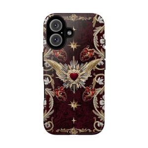 May include: A burgundy phone case with a detailed design. The case features a central heart with gold wings, surrounded by gold stars, hearts, and floral patterns. The camera lenses are visible at the top.