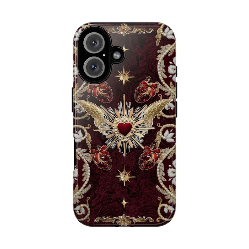 May include: A burgundy phone case with a detailed design. The case features a central heart with gold wings, surrounded by gold stars, hearts, and floral patterns. The camera lenses are visible at the top.