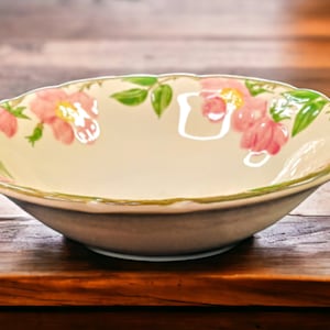 May include: A white ceramic bowl with a scalloped rim and a floral design featuring pink flowers and green leaves.