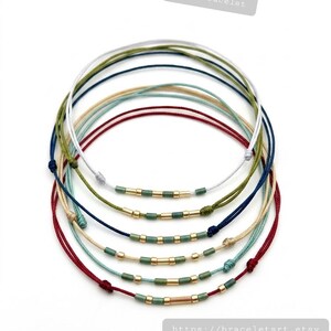 May include: Ankle bracelets in various colours, including red, green, and blue, with gold-coloured beads. The bracelets are made of cord and are knotted. Text on the image reads "Ankle bracelet" and a website address.